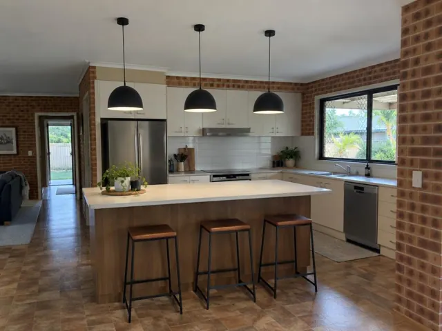 Three black pendant lights over a kitchen island in a brick home interior in Reedy Creek